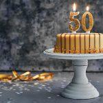 Birthday cake on a cake stand topped with a candle shaped like the number 