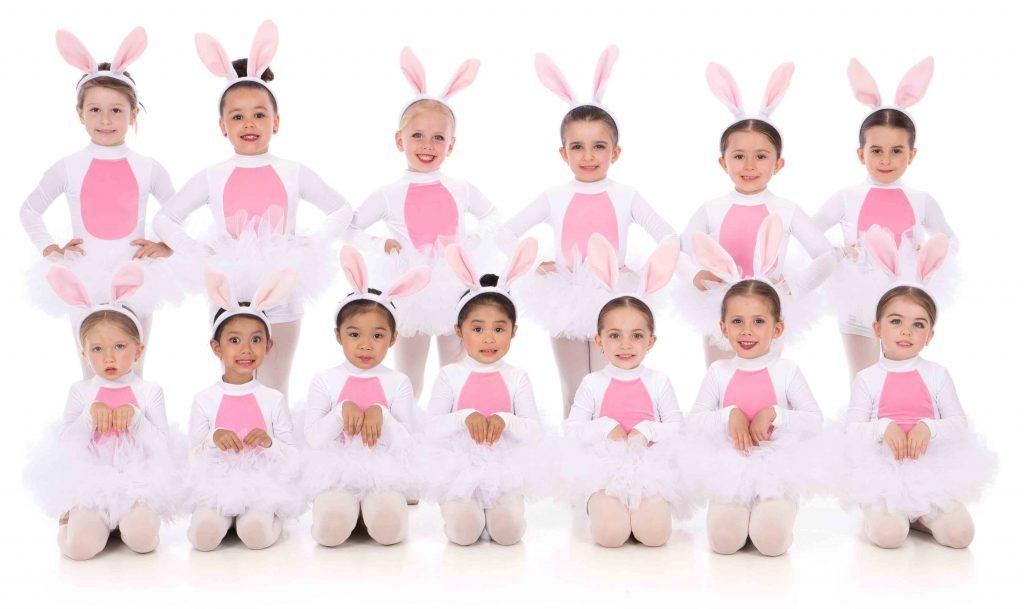 A group of young DanzArts Toronto dance students wearing bunny costumes posing in two rows for a photo.