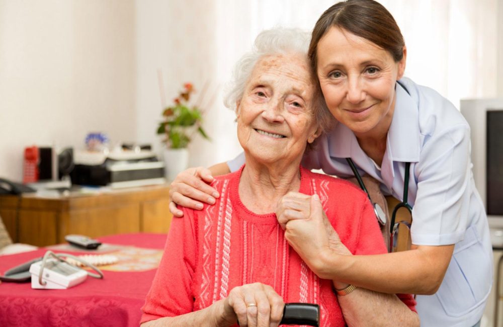 A nurse and a senior pose for a photo.